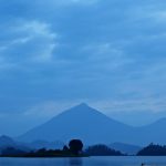 Scenic view of Lake Bunyonyi in Uganda, featuring serene waters, lush greenery, traditional dugout canoes, and vibrant birdlife.