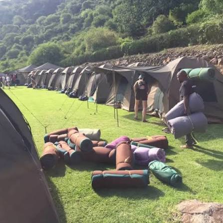 Campers enjoying sunrise overlooking Ngorongoro Crater rim surrounded by scenic wilderness views.